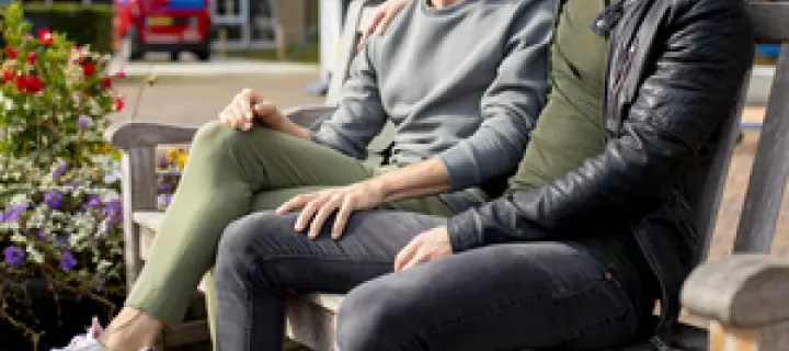 Twee mannen zitten op een bankje voor de entree van het Diakonessenhuis